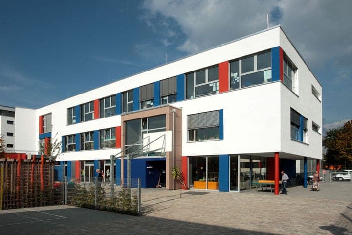 Private Grundschule HVD in Fürth, Ansicht der dreigeschossigen Fassade mit blauen und roten Fensterlaibungen